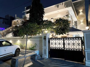 A gated residential property at night with a white car parked in front.
