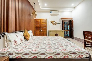 A hotel room with a bed, a wooden wardrobe, a small desk, and a chair. - Wonderful 3-bedroom house in Jaipur perfect for your getaway/ Free wif-fi/Family (Jaipur)