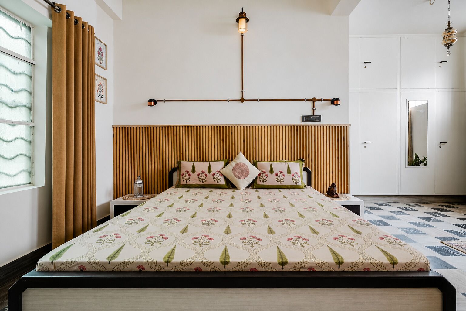 Een slaapkamer met een bed, een houten hoofdbord, nachtkastjes, een hanglamp en een beddengoed met een patroon.