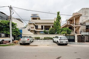 A residential area with two parked cars, a multi-story house with a balcony, and a gated entrance. - Wonderful 3-bedroom house in Jaipur perfect for your getaway/ Free wif-fi/Family (Jaipur)