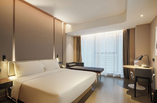 Une chambre d’hôtel avec un grand lit, un bureau, une chaise et une vue sur un immeuble par la fenêtre.