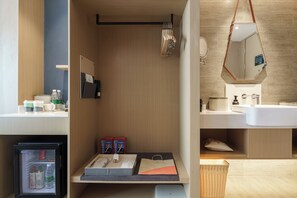 Une salle de bain moderne avec un meuble-lavabo en bois, un miroir et un évier. On y trouve une petite étagère avec des articles de toilette et un panier.