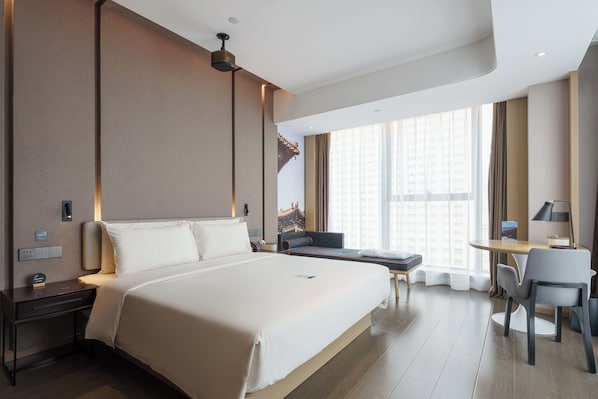 A modern hotel room with a large bed, a desk, and a chair.