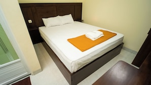 Een enkel bed met een houten frame, witte beddengoed en een oranje deken.