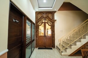 A hallway with a wooden door labeled 'OFFICE,' a decorative wooden archway, and a staircase with wooden railings. - Bintang Samudra Hotel (Jepara)