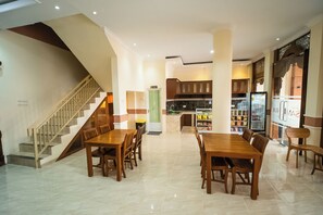 Un amplio comedor con escalera, cocina y nevera llena de bebidas.