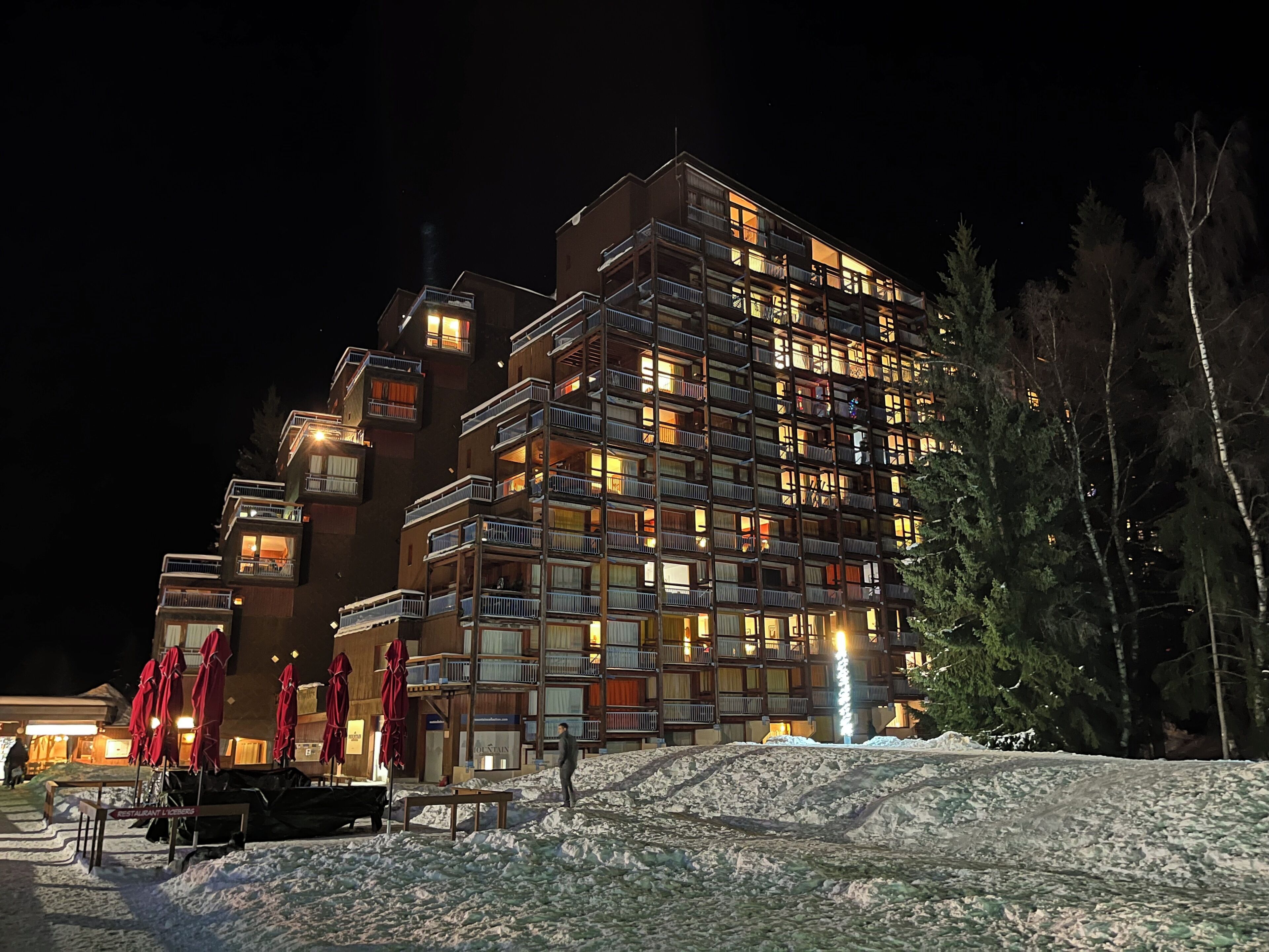 Een hotel met meerdere verdiepingen, balkons, een skilift en een besneeuwde omgeving.