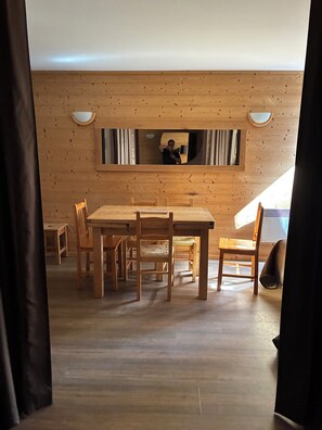 A wooden interior with a dining table and chairs, a small window, and a mirror on the wall. - ❄️ LES ARCS 1800 ❄️ - Luxury Apartment – Les Arcs 1800 ⛷️ (Bourg-Saint-Maurice)