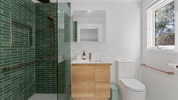 A modern bathroom with a shower, a toilet, and a sink.