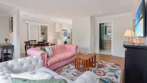 Ein Wohnzimmer mit einem rosafarbenen Sofa, einem Essbereich und einer Küche im Hintergrund.