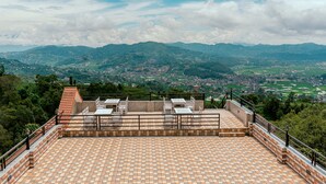 A rooftop terrace with a tiled floor, a railing, and a view of a cityscape and mountains in the distance. - Landmark Diamond Hill (Panaoti)
