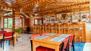 A wooden interior with a bar area, seating, and a Coca-Cola refrigerator. - Landmark Diamond Hill (Panaoti)