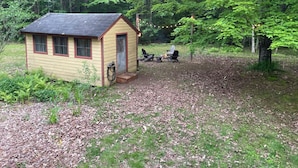 Eine kleine Holzhütte mit Veranda, umgeben von einem Waldgebiet.