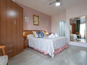 A bedroom with a wooden wardrobe, a bed with patterned bedding, a bedside table, and a large mirror. - Sunstay Flat Duquesa Torremolinos (Torremolinos)