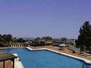 A swimming pool with lounge chairs and umbrellas, surrounded by buildings and a clear sky. - Sunstay Flat Duquesa Torremolinos (Torremolinos)