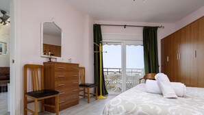 Un dormitorio con cama, cómoda, silla, espejo y balcón con vistas.