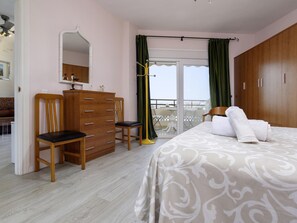 A bedroom with a bed, a dresser, a chair, a mirror, and a balcony with a view. - Sunstay Flat Duquesa Torremolinos (Torremolinos)