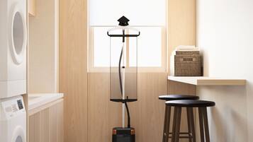 A laundry room with a washing machine, a drying rack, and a vacuum cleaner.