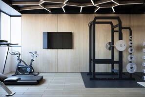 A modern gym with exercise equipment, a television, and a wooden wall. - AMAROU Saigon  (Ho Chi Minh City)