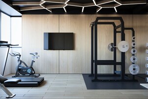 A modern gym with exercise equipment, a television, and a wooden wall.