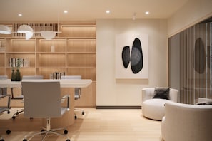 A modern interior with a conference table, chairs, a bookshelf, and a wall-mounted abstract art piece. - AMAROU Saigon (Ho Chi Minh City)