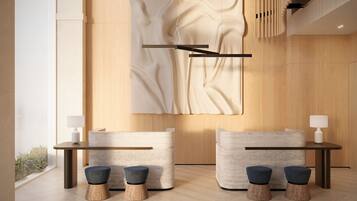 Een modern interieur met een houten wand, een groot abstract kunstwerk, een receptiebalie en twee zithoeken met krukken.