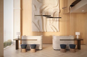 A modern interior with a wooden wall, a large abstract artwork, a reception desk, and two seating areas with stools.