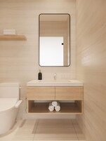 Un baño moderno con un lavamanos blanco, un espejo encima y un inodoro a la izquierda.