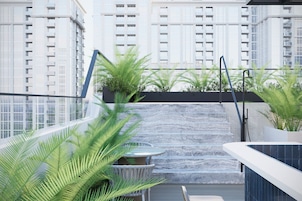 Une terrasse sur le toit offrant une vue sur les gratte-ciel, agrémentée d’un élément aquatique et de plantes en pot.