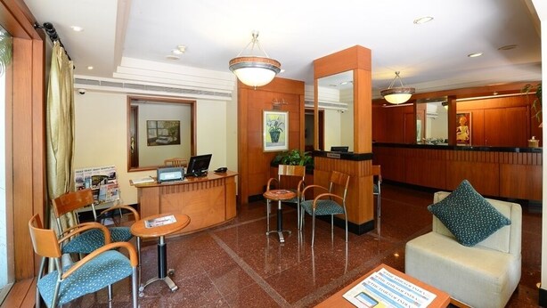 Una hall d'albergo con reception, area salotto e uno specchio.