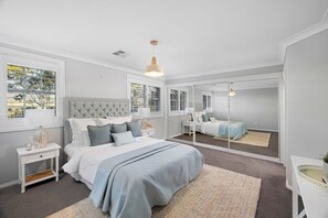 A bedroom with a large bed, a mirror, and a window with blinds. - Carinya Centennial Bowral Spa Retreat (Bowral)