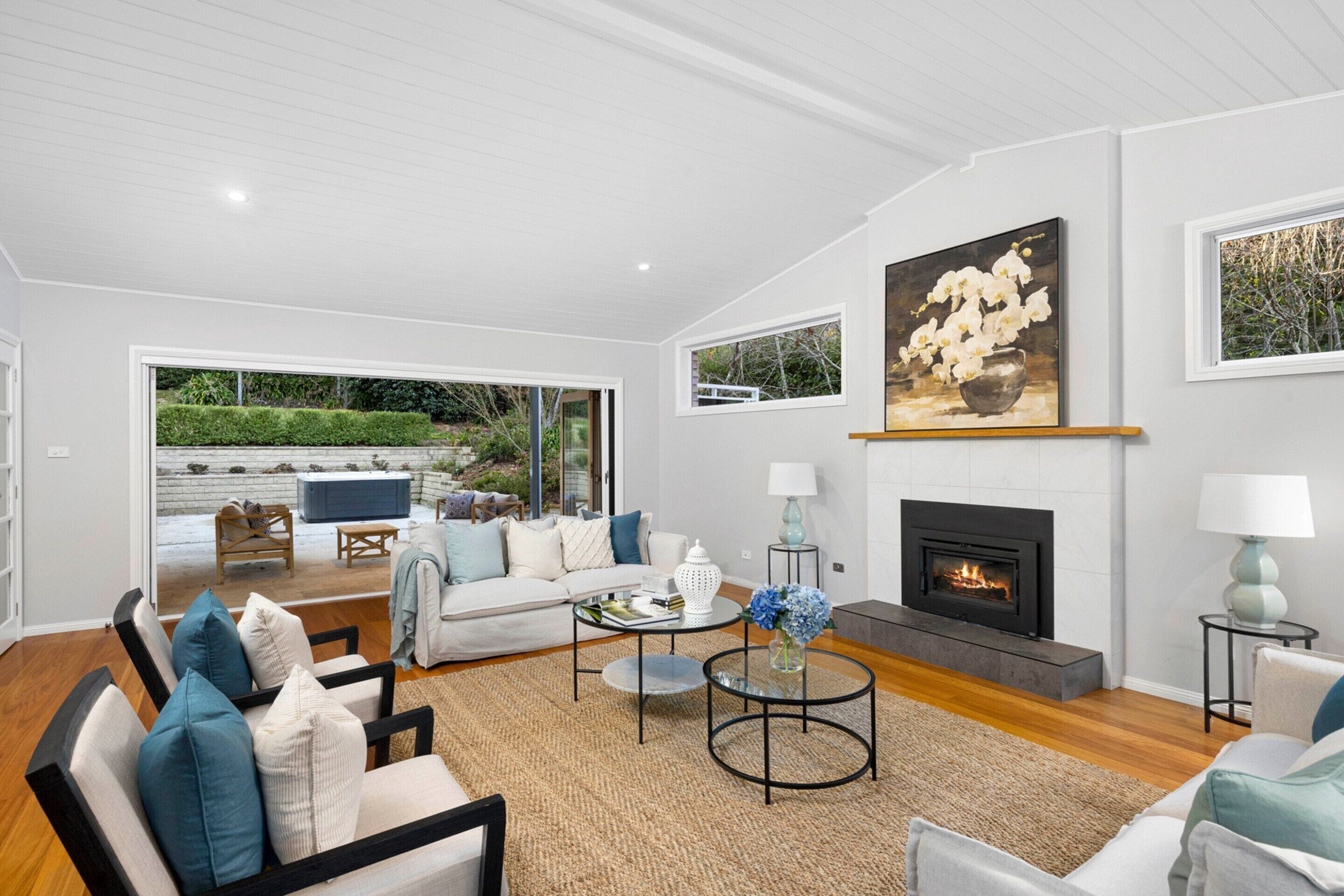 A modern living room with a fireplace, comfortable seating, and a view of the outdoors.