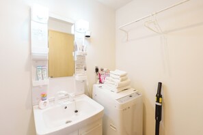Ein Badezimmer mit Waschbecken, Spiegel, Handtuchhalter und einer Waschmaschine.