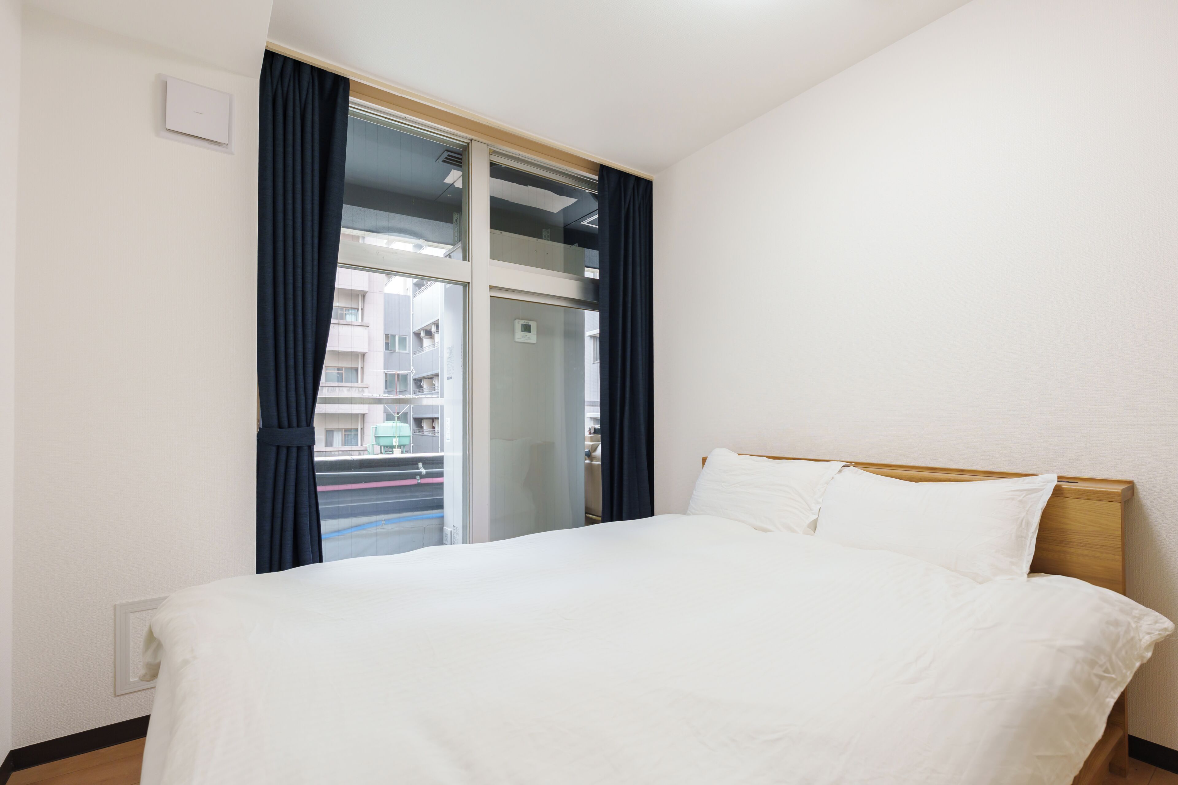 Habitación de hotel con cama, ventana con cortinas y vistas al exterior.