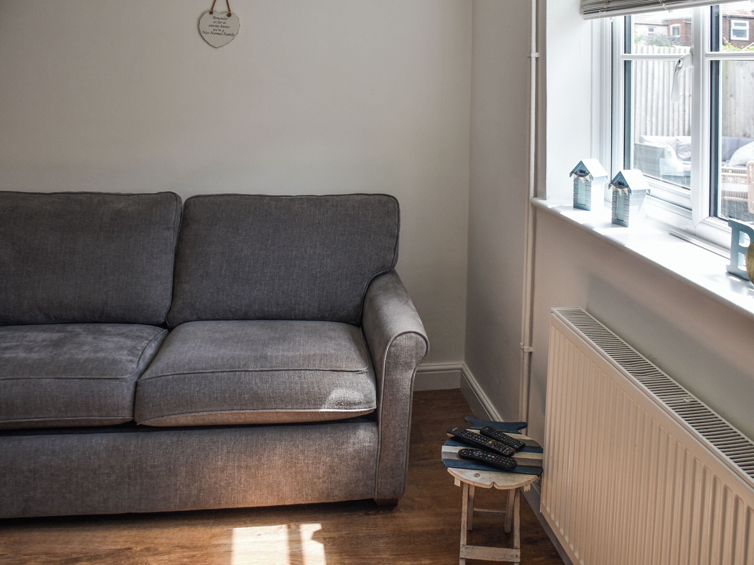 Un sofà gris en una habitació amb un radiador i una finestra que dona a l'exterior.