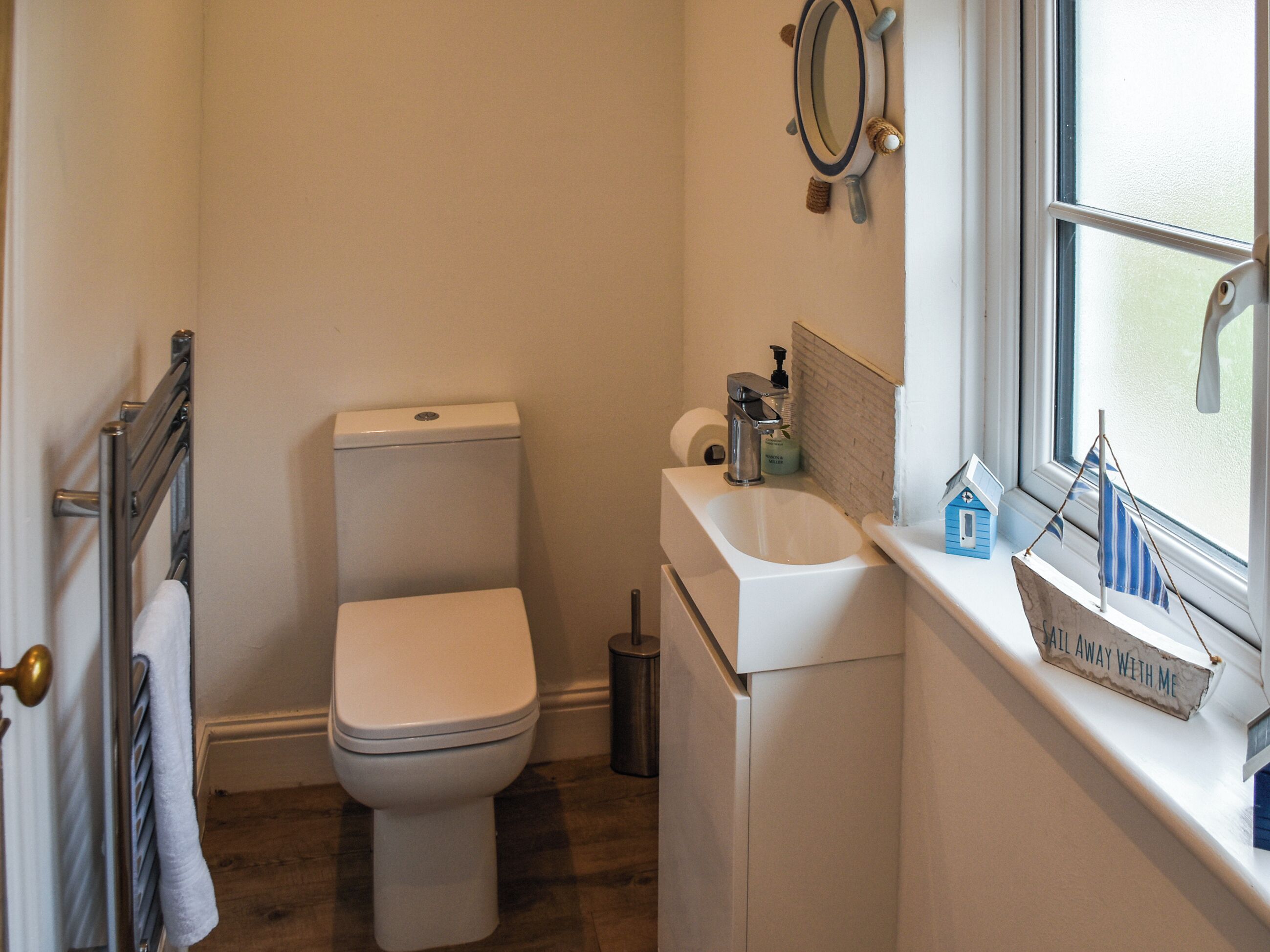 Une petite salle de bain avec des toilettes, un lavabo et une fenêtre.