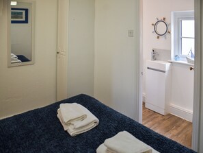 Ein Hotelzimmer mit Bett, einem Badezimmer mit Waschbecken und Spiegel sowie einer Tür zu einem weiteren Raum.