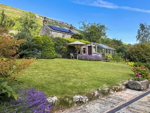 A house with a sloped roof, a conservatory, and a well-maintained lawn.