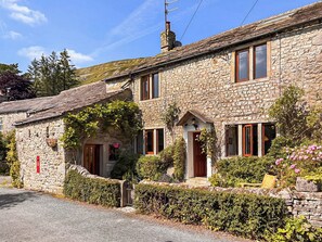 A stone building with a traditional design, featuring a central entrance with a door and windows on either side. - 3 bedroom accommodation in Hawkswick (Hawkswick)