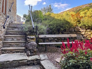 A stone staircase leading up to a wooden bench, surrounded by a stone wall and various plants. - 3 bedroom accommodation in Hawkswick (Hawkswick)