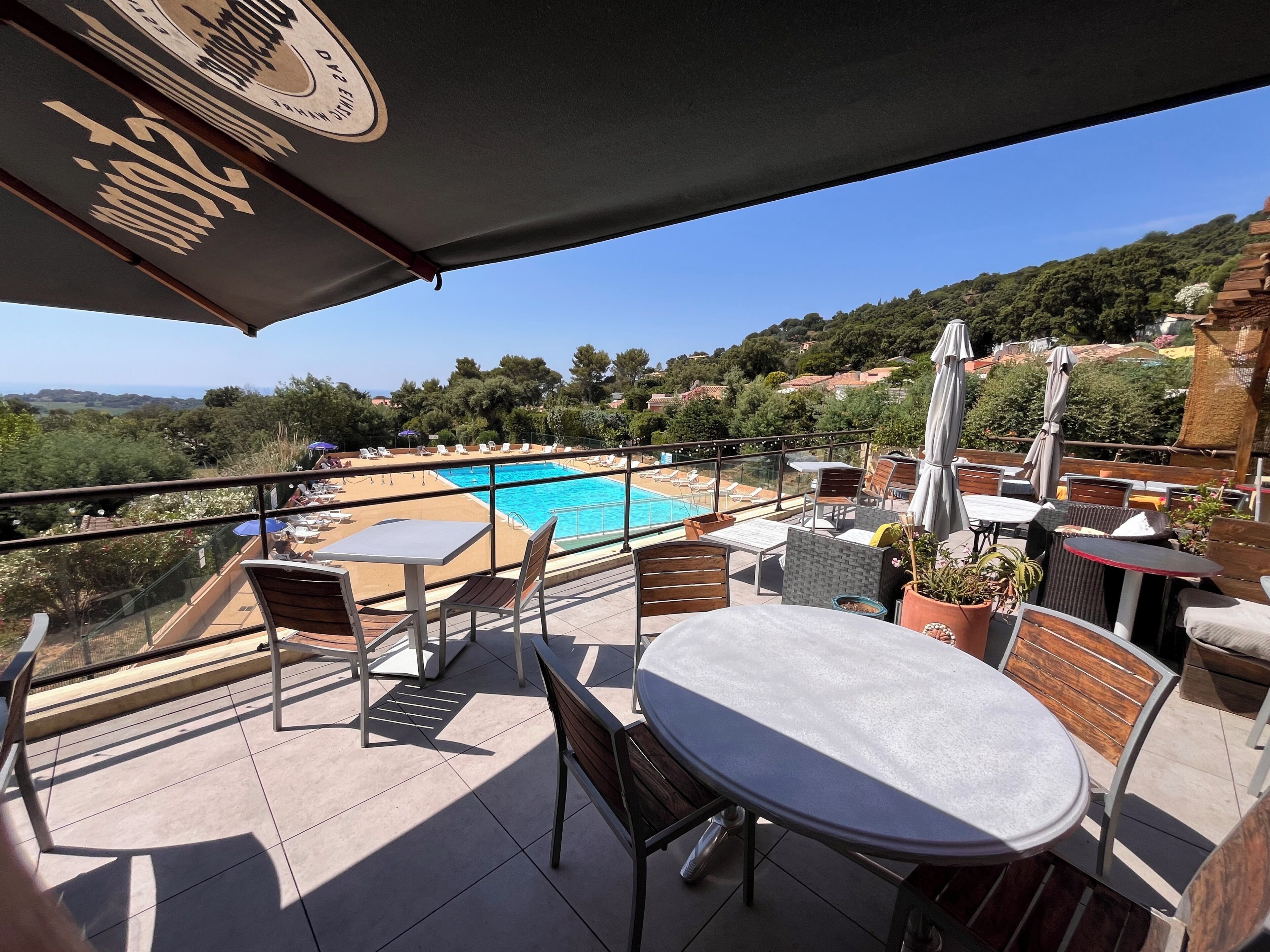 A rooftop terrace with a swimming pool, outdoor seating, and a view of the surrounding landscape.