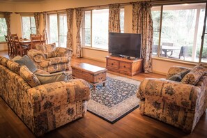 A living room with a sofa set, a coffee table, a TV on a wooden stand, and a patterned rug.