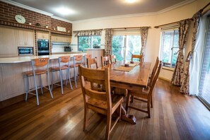 A kitchen with wooden cabinets, a brick wall, and a dining area with a wooden table and chairs.