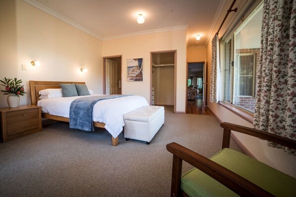A bedroom with a bed, bedside table, and a window with curtains.