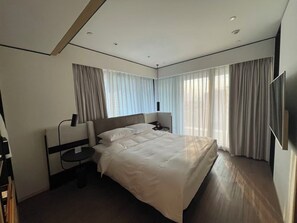 A modern hotel room with a large bed, a bedside table, a TV, and a window with curtains. - Nester Finn Suites Entertainment Toronto (Toronto)