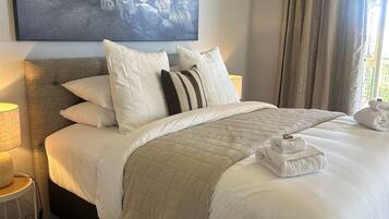 A neatly made bed with a quilted blanket, a pillow with stripes, and a folded towel on the side.