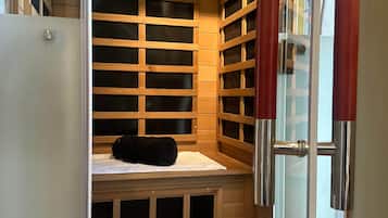 A sauna with wooden benches, a glass door, and a towel on the floor.