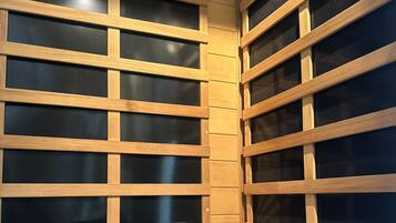 Una sauna con listelli di legno e un asciugamano su un tappetino bianco.