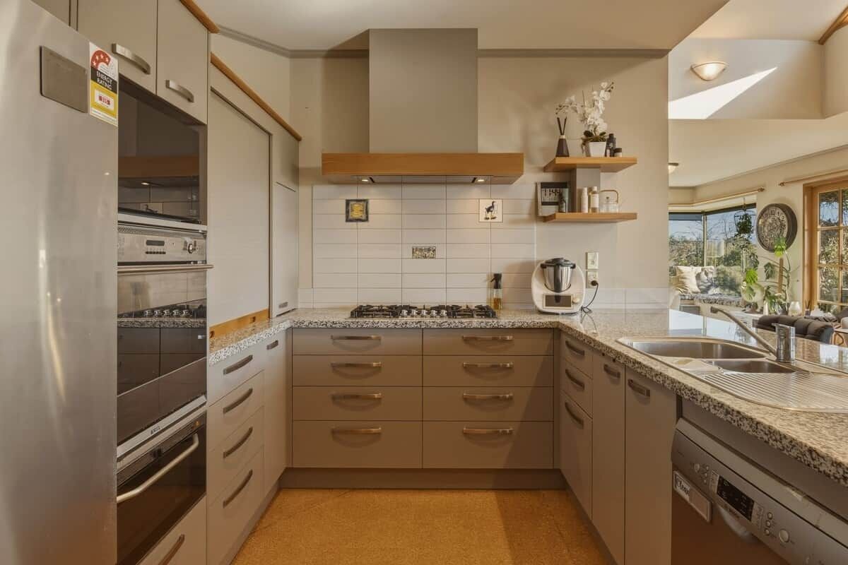 A modern kitchen with stainless steel appliances, a central island, and a view to the outdoors.