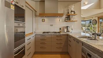 A modern kitchen with stainless steel appliances, a central island, and a view to the outdoors.